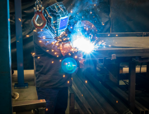 man welding with blue and orange sparks