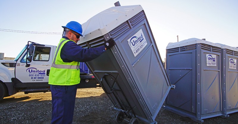 man rolling a portable toilet