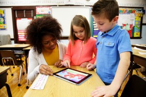teacher and two students looking at a tablet