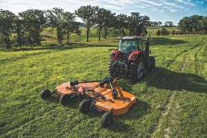 man operating a batwing mower equipment
