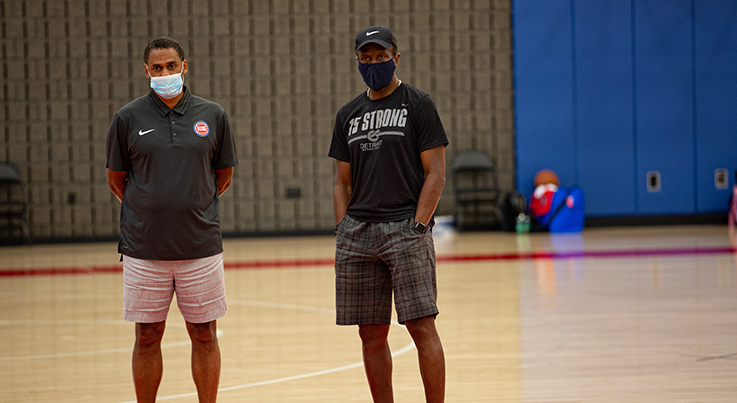 men in an indoor basketball court wearing face masks