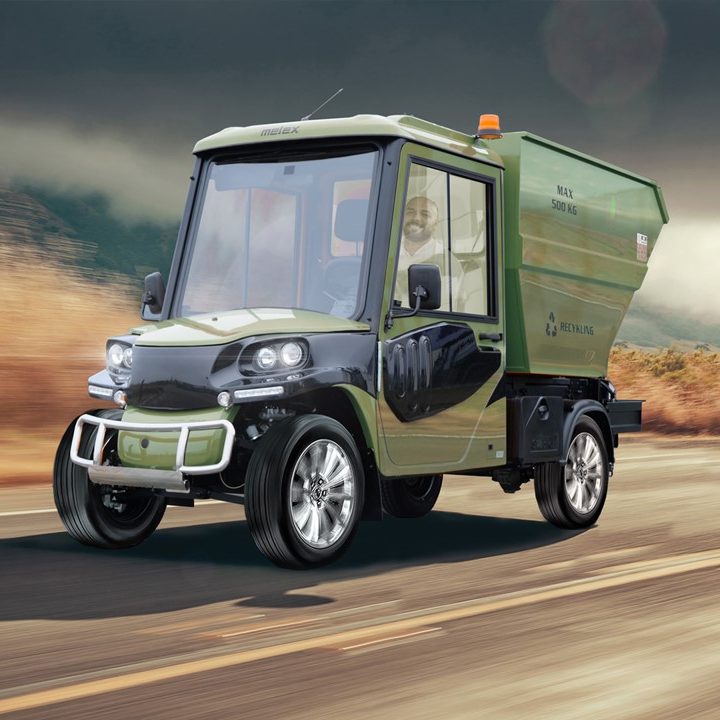 Photo depicting a compact green garbage truck with a person riding on it