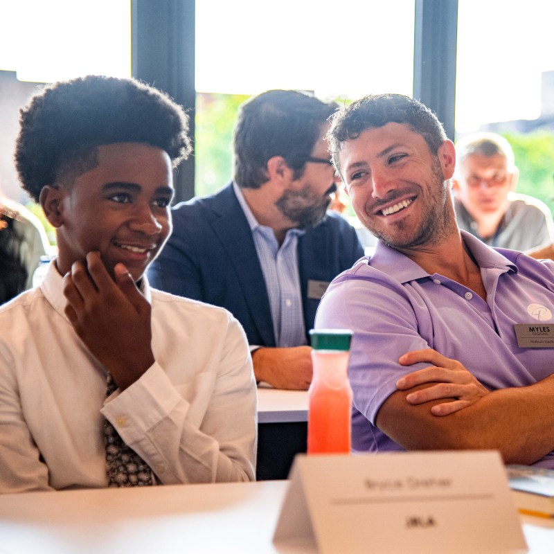 2 men sitting and smiling on each other