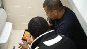 2 men both sitting and looking at a mobile phone in landscape view