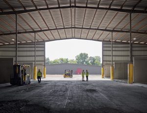 mostly empty warehouse open door and people standing around