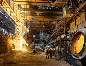 industrial equipment in a large space with workers showing small at the bottom of the image