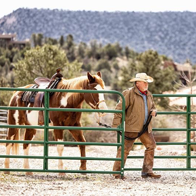 image of an older farmer leading a horse out of the pen