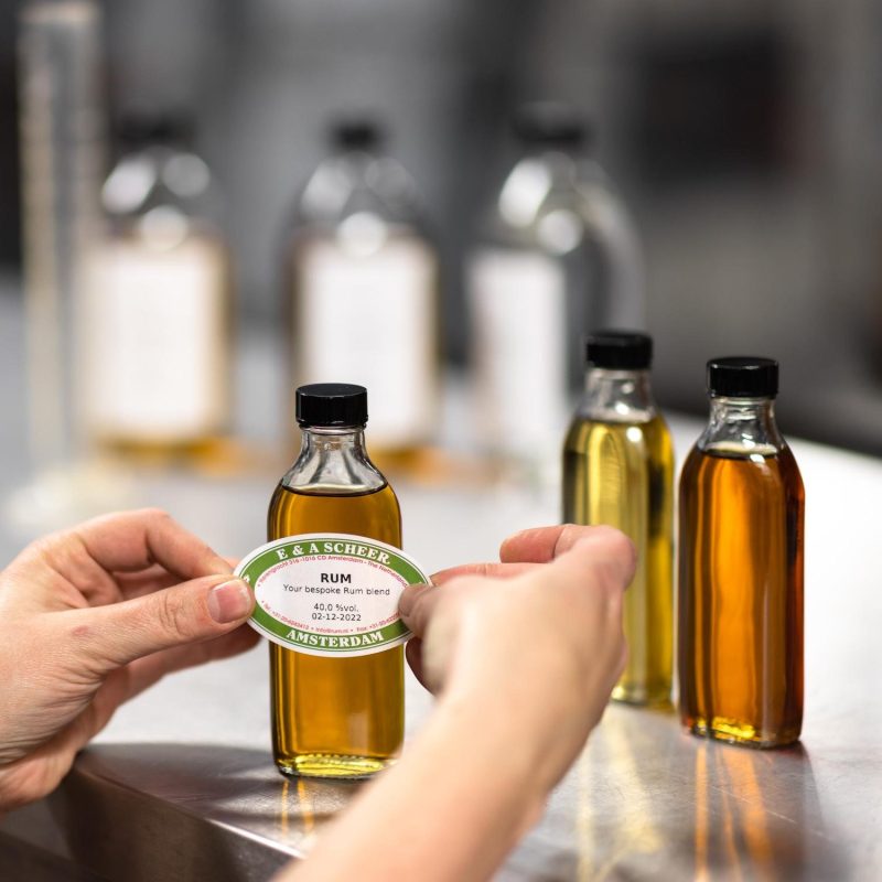 The image shows a person holding a glass bottle patching some kind of a paper logo.