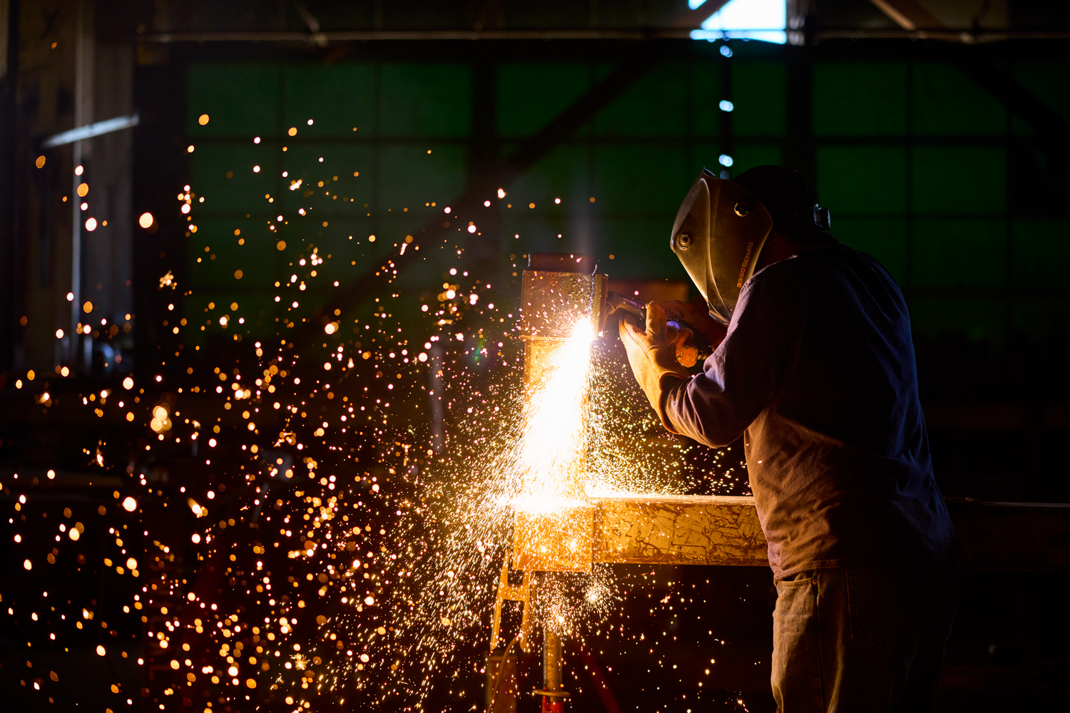 man is inside a factory welding steel metal.