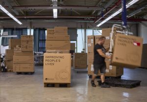 wheel chair factory a person using machinery to move a large cardboard box with more boxes around him