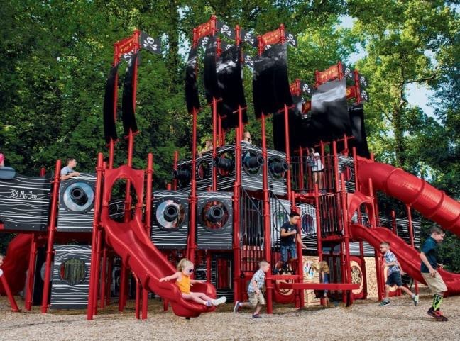 Group of children climbing and playing on a large multilevel playground structure with slides, nets, and towers. | Platinum Equity