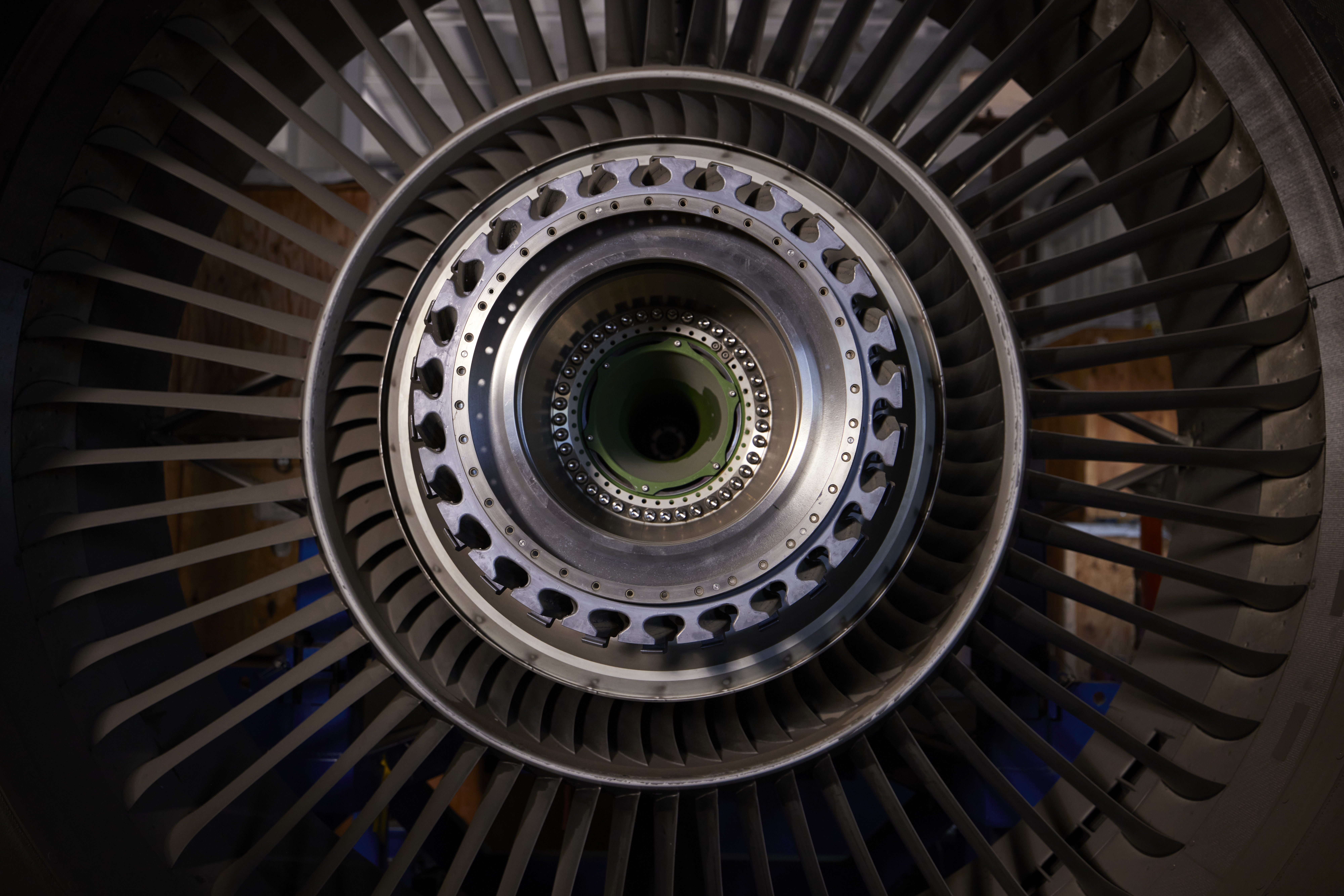Close-up view of a large aircraft engine turbine with metal fan blades and a detailed central hub inside an industrial facility. | Platinum Equity